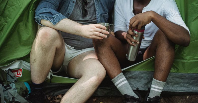 User-Friendly Experience - Diverse friends having rest in tent with tea in thermos